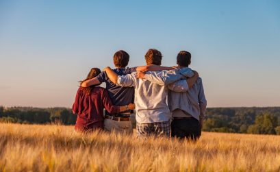 Four people enjoying a group hug in a field.