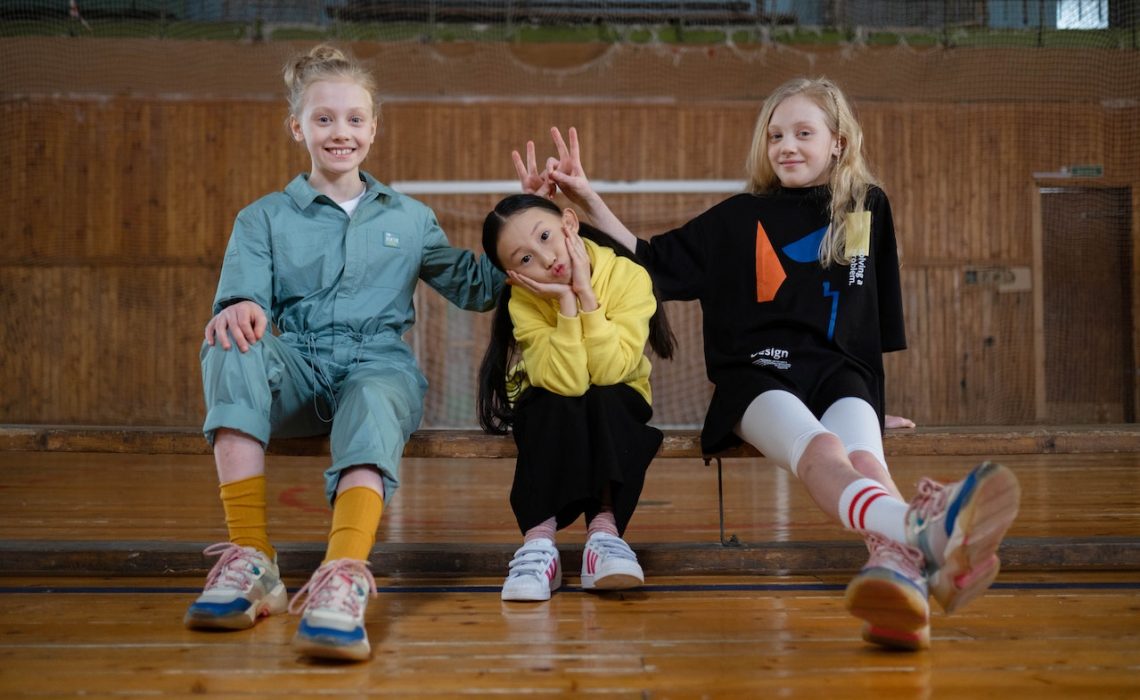 two girls doing bunny ears over another girl