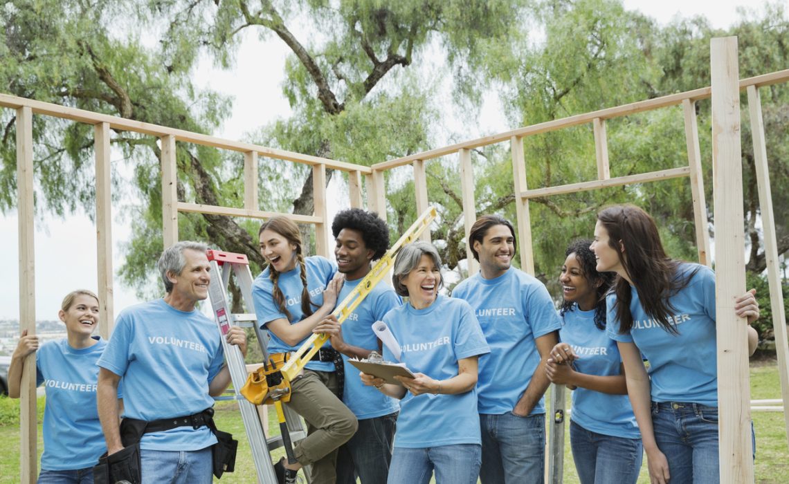 Group of cheerful volunteers with construction frame in at park