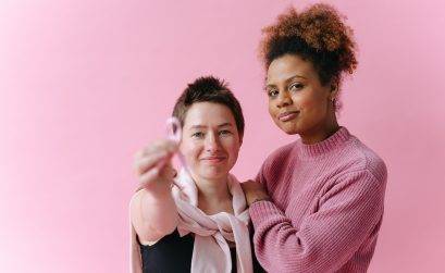 two women in pink holding up a breast cancer awareness ribbon