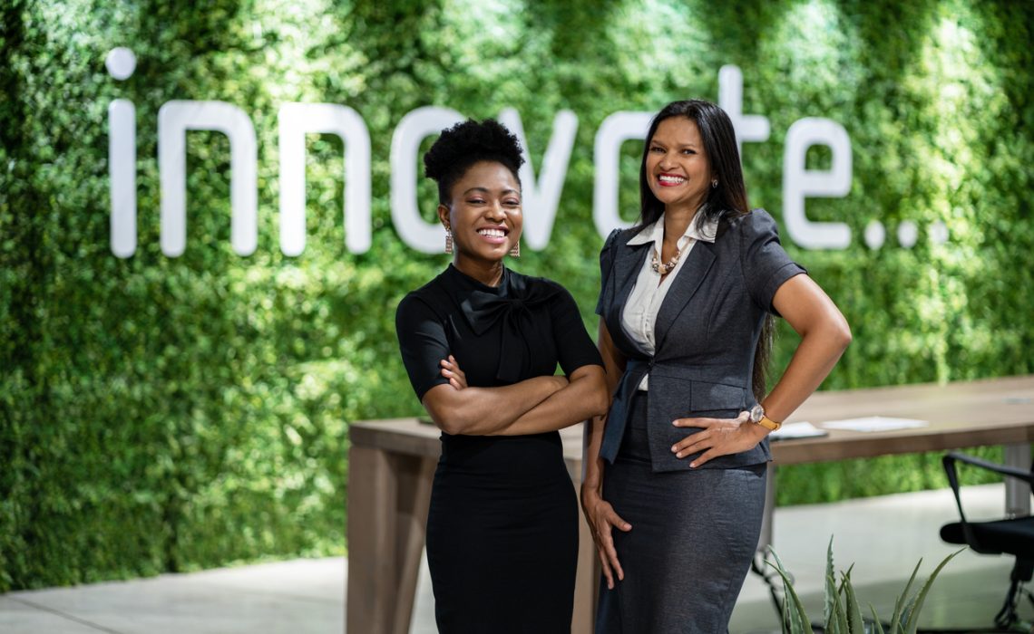 Portrait of a diverse young African business woman smiling while standing together in an eco-friendly modern office space