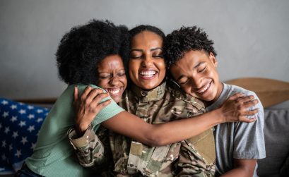 Soldier mother embracing son and daughter at home