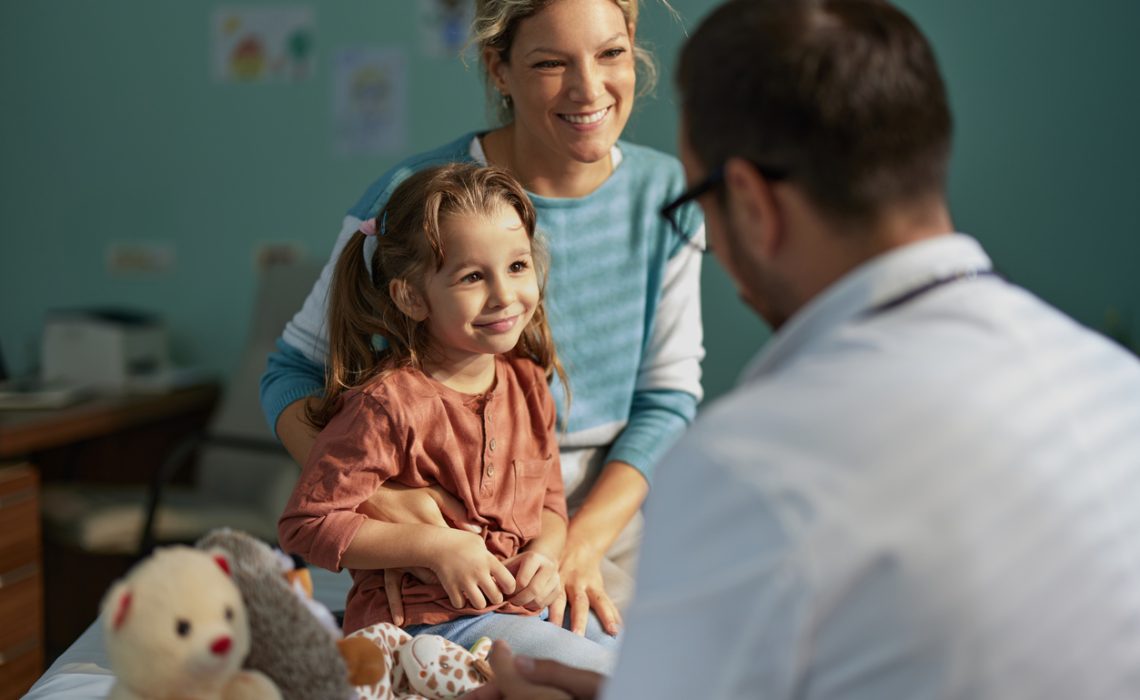 Smiling girl having an appointment with her mother at pediatricians'.