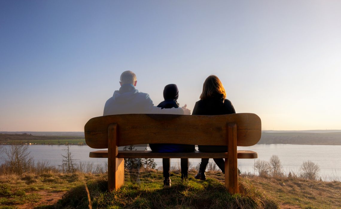 Loss of a family member depicted with slightly transparent man with family on a park bench