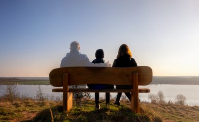 Loss of a family member depicted with slightly transparent man with family on a park bench