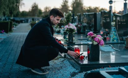 Man in the cemetery holding a red rose in his hand