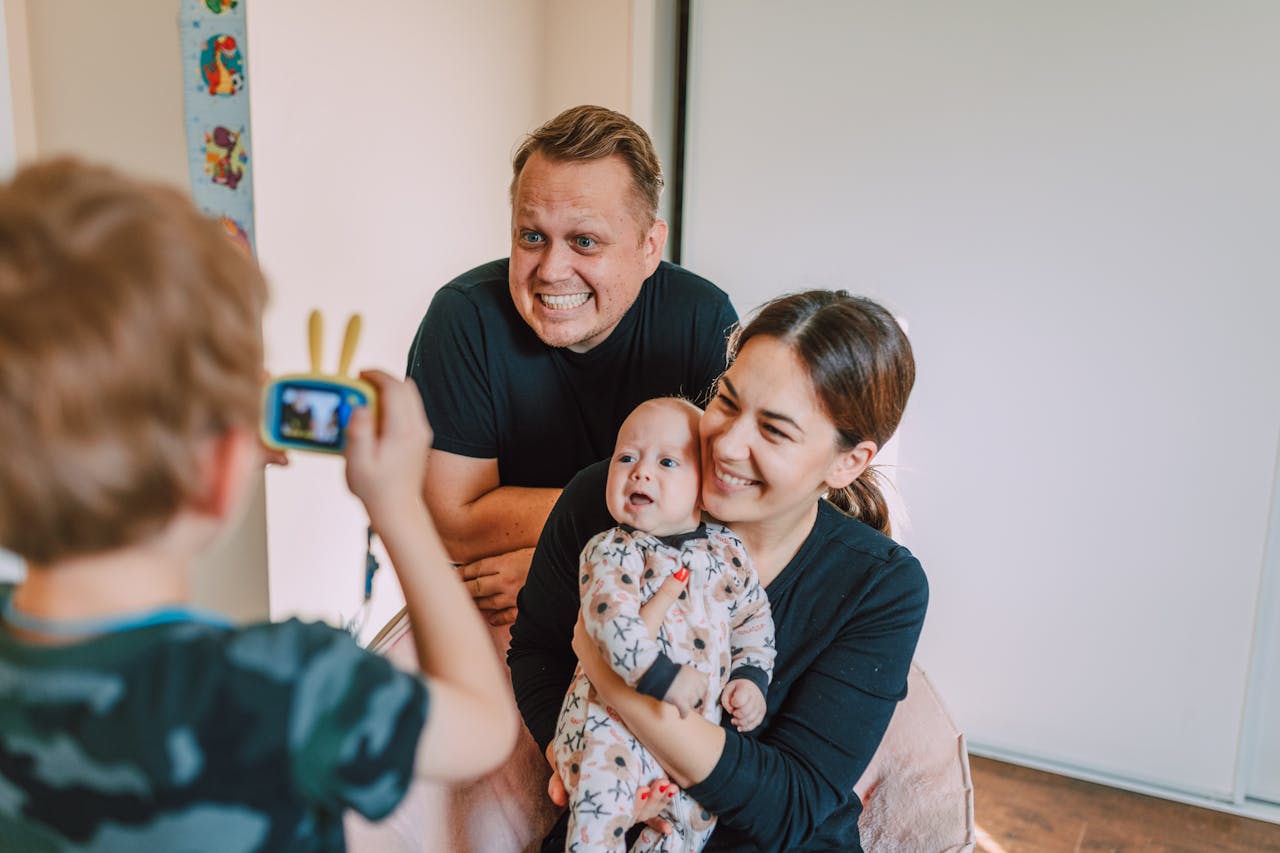 A Boy Taking a Picture of a Couple with Their Baby